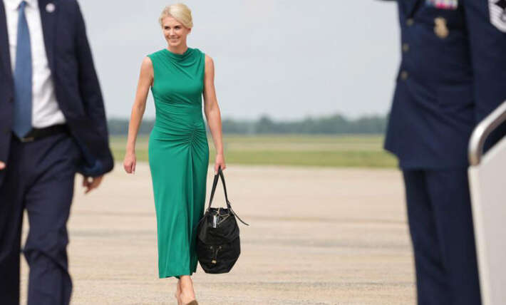 Grinning Natalie Harp struggles with massive bag as she joins Trump in Texas